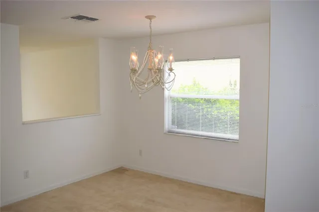 an empty room with chandelier fan and windows