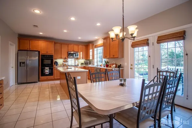 a dining room filled counter top space a refrigerator a dining table and chairs