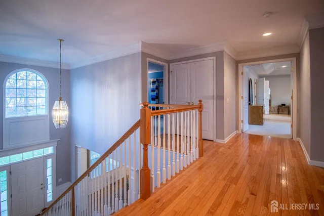 a view of a hallway to a livingroom with wooden floor and stairs