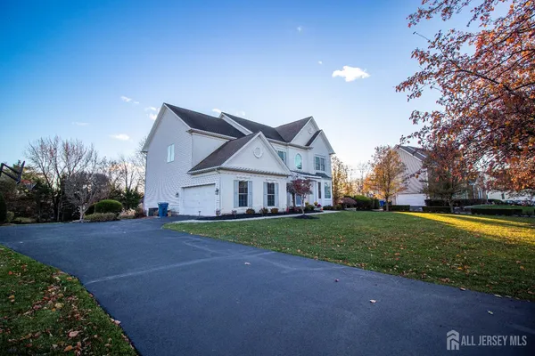 a view of a house next to a big yard with large trees