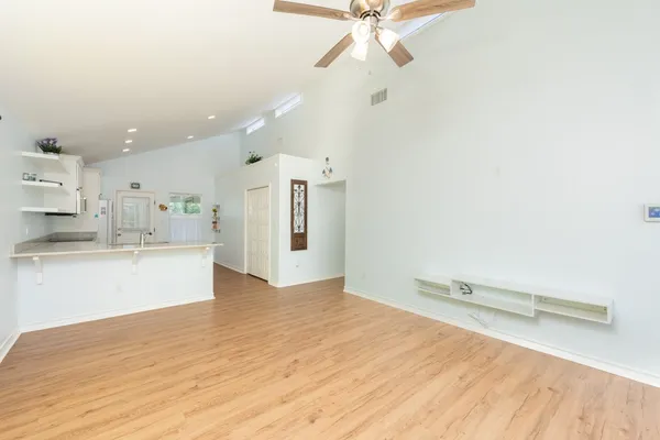 a large white kitchen with a lot of counter space and wooden floor