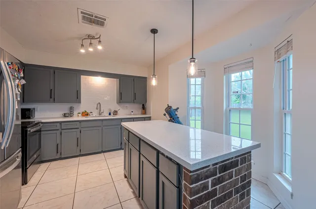 a kitchen with a stove a refrigerator a sink dishwasher with a dining table and chairs