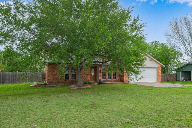 a front view of house with a garden and trees