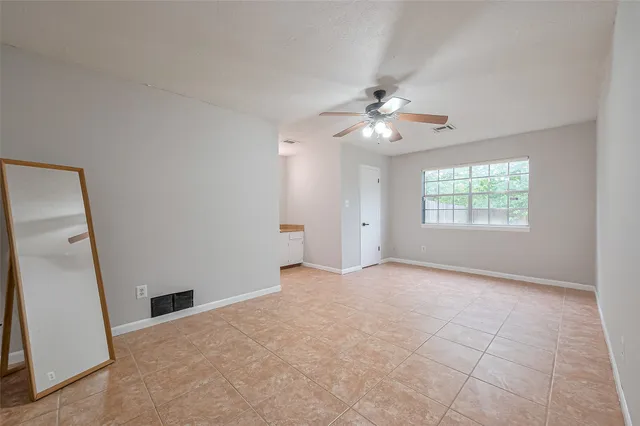 an empty room with windows and a ceiling fan
