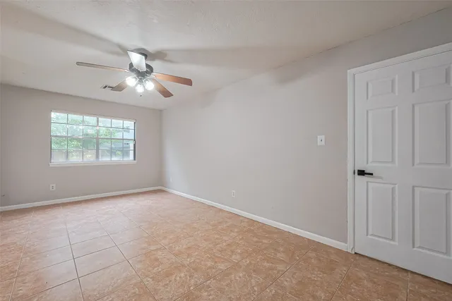 an empty room with windows and fan