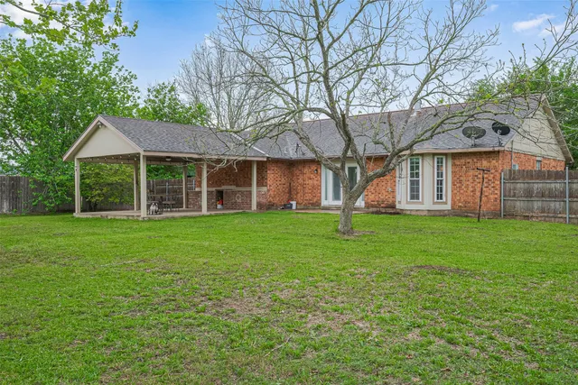 a view of a house next to a big yard and large trees