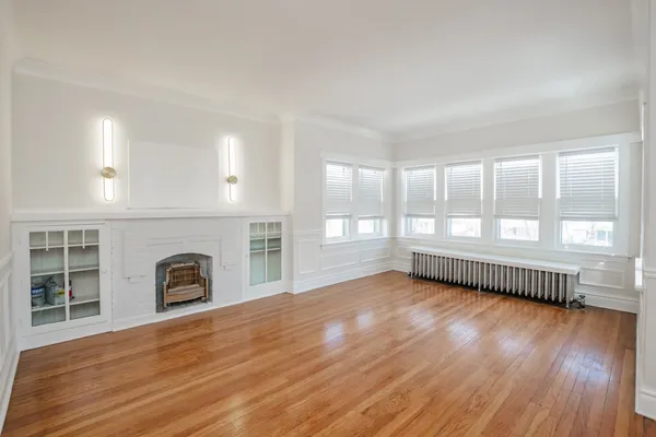 a view of empty room with wooden floor and fireplace