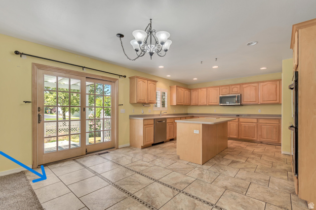 546 Wheatridge Road Tooele, UT 84074 - Photo 12 of 49 Kitchen featuring extensive light wood cabinetry, a central island, stainless steel appliances, and custom tile (blue arrow) with decorative inlay