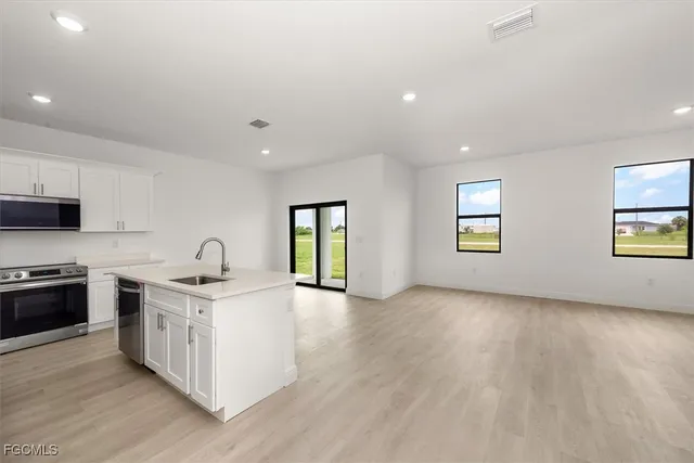 a kitchen with stainless steel appliances granite countertop a stove a sink and a refrigerator with wooden floors