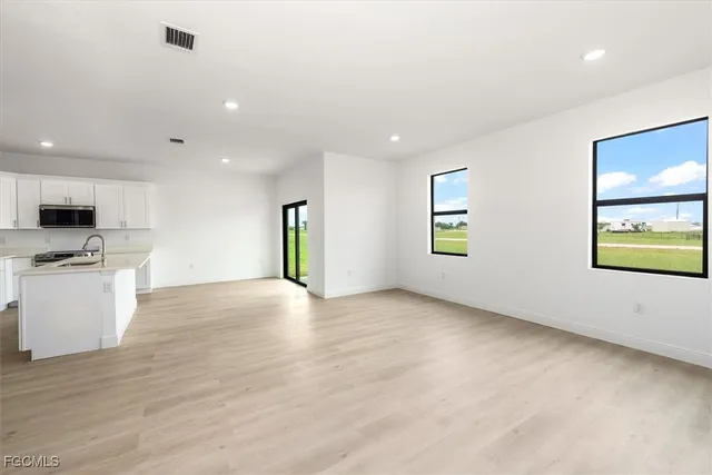 a view of an empty room with window and wooden floor