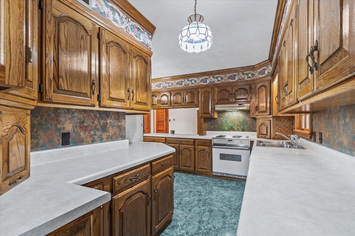 102 Linden Street Grand Junction, TN 38039 - Photo 13 of 37 Kitchen with light countertops, white range with electric cooktop, ornamental molding, tasteful backsplash, and brown cabinets