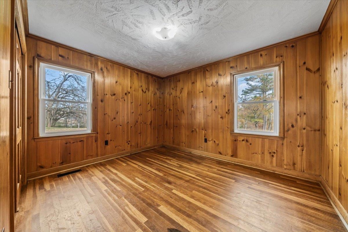 102 Linden Street Grand Junction, TN 38039 - Photo 24 of 37 Empty room with wood walls, light wood-type flooring, a textured ceiling, and ornamental molding