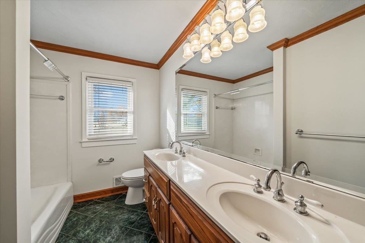 102 Linden Street Grand Junction, TN 38039 - Photo 27 of 37 Full bath with double vanity, shower / tub combination, a chandelier, dark tile patterned floors, and crown molding