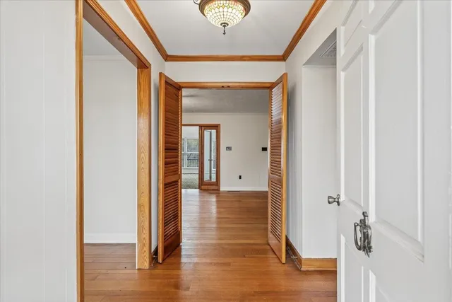 a view of a hallway with wooden floor and a bathroom