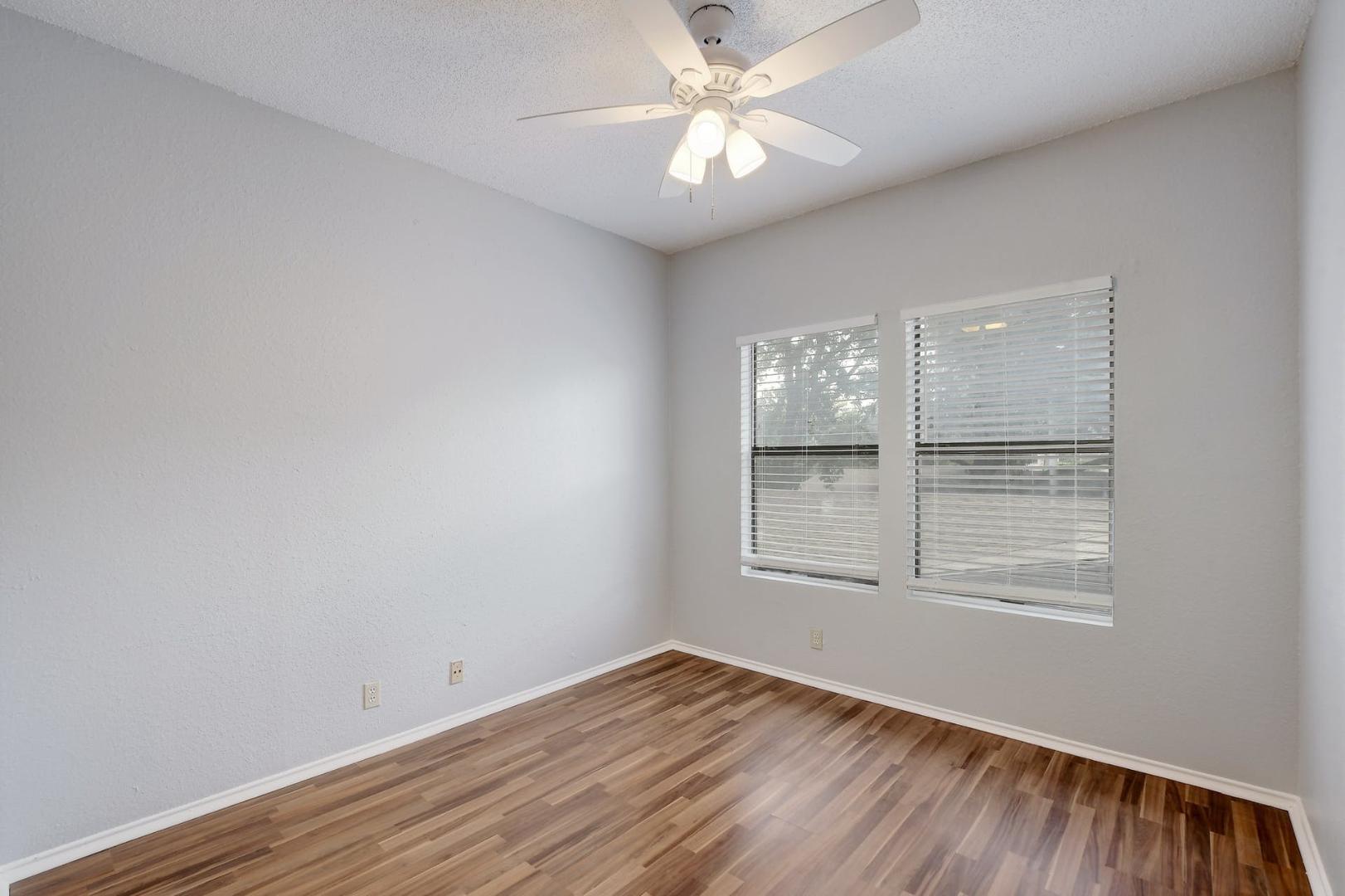 2804 Rio Grande Street, Unit 310 Austin, TX 78705 - Photo 12 of 22 Hardwood floors and ample natural light fill this inviting bedroom, complete with a modern ceiling fan.