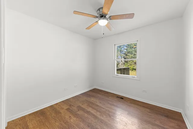 an empty room with a window and a fan