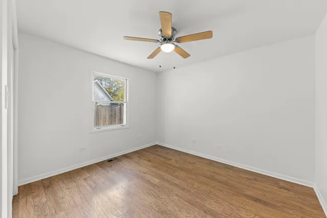 an empty room with a window and a ceiling fan
