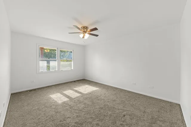an empty room with windows and ceiling fan