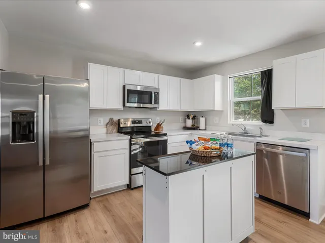 a kitchen with cabinets stainless steel appliances a sink and a window