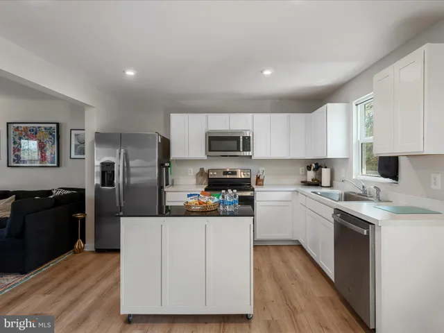 a kitchen with stainless steel appliances granite countertop a stove top oven a refrigerator a sink and dishwasher with wooden floor