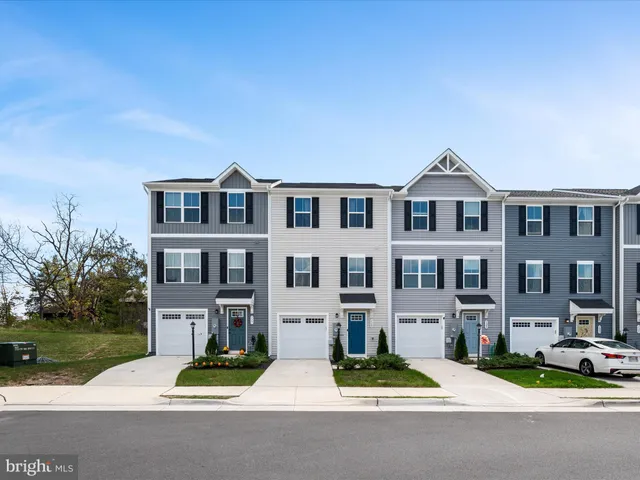 a front view of a residential apartment building with a yard and garage