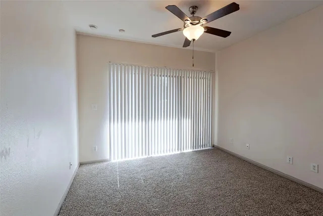 an empty room with closet and a ceiling fan