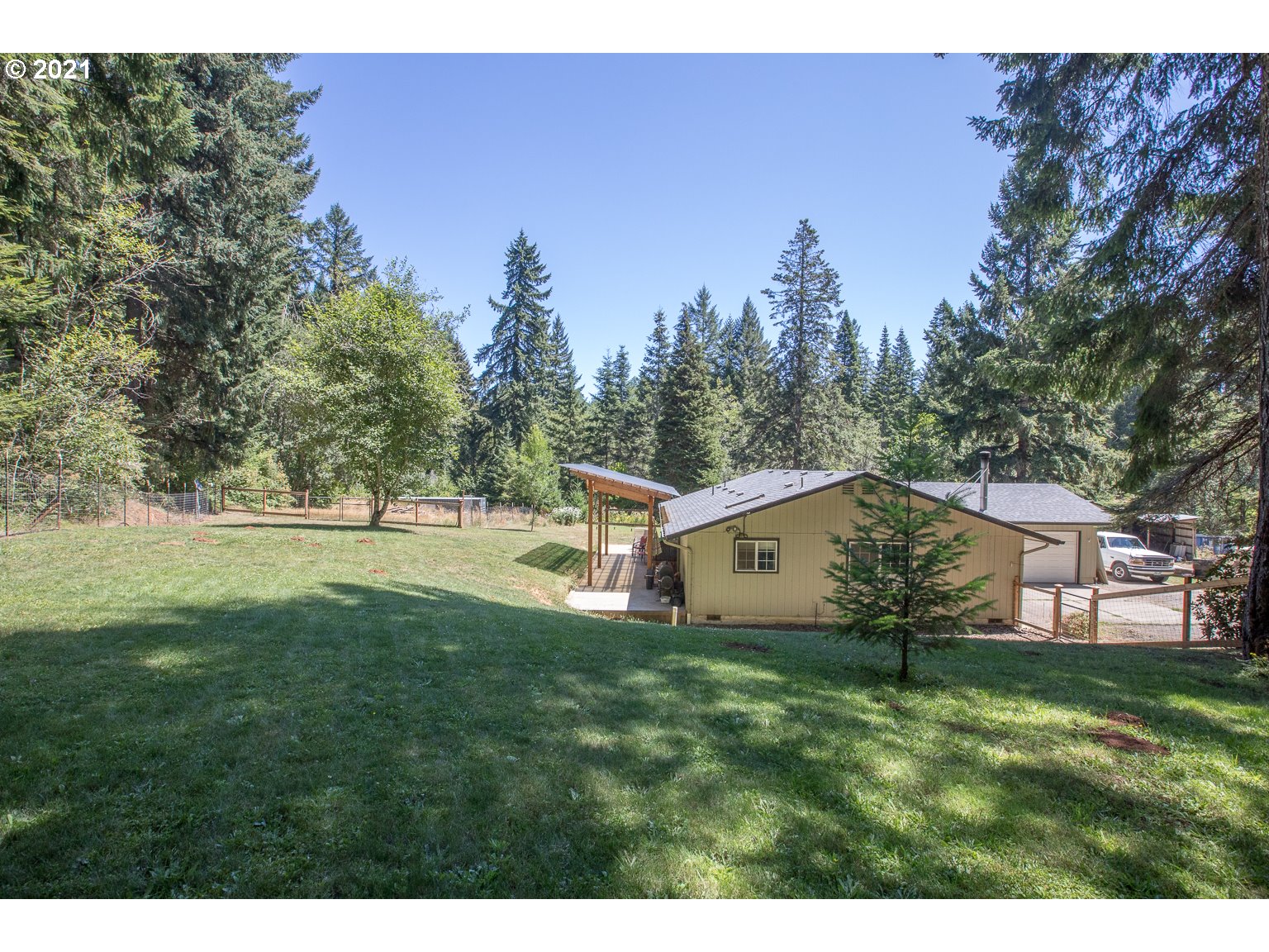 a view of a white house with a big yard and large trees