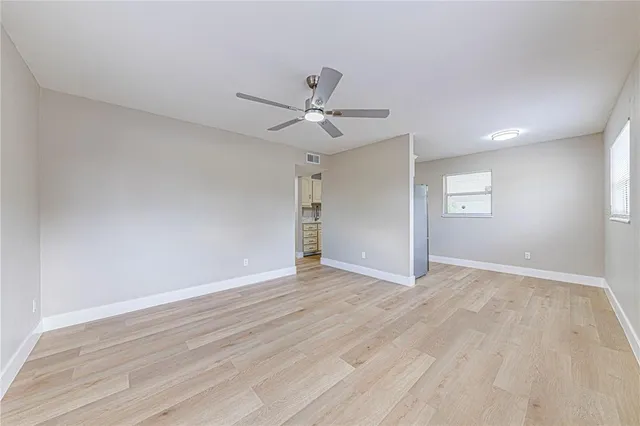 a view of an empty room with window and wooden floor