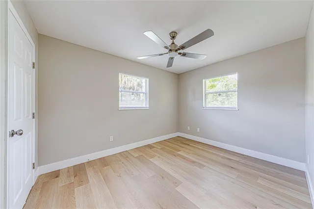 a view of empty room with wooden floor and fan