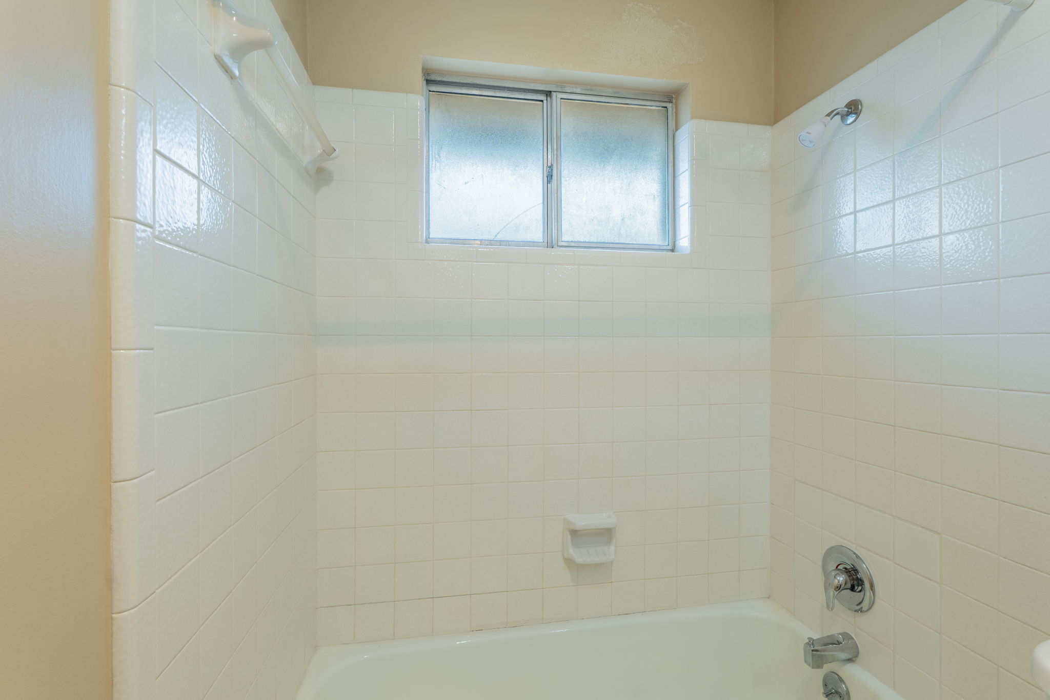 5628 Wagon Train Road Austin, TX 78749 - Photo 18 of 26 Clean tile surrounds the shower and tub enclosure beneath a privacy window.