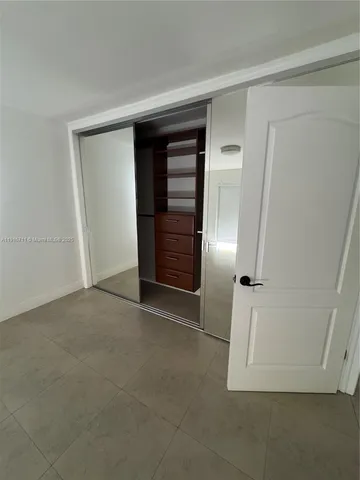 an empty room with closet and refrigerator