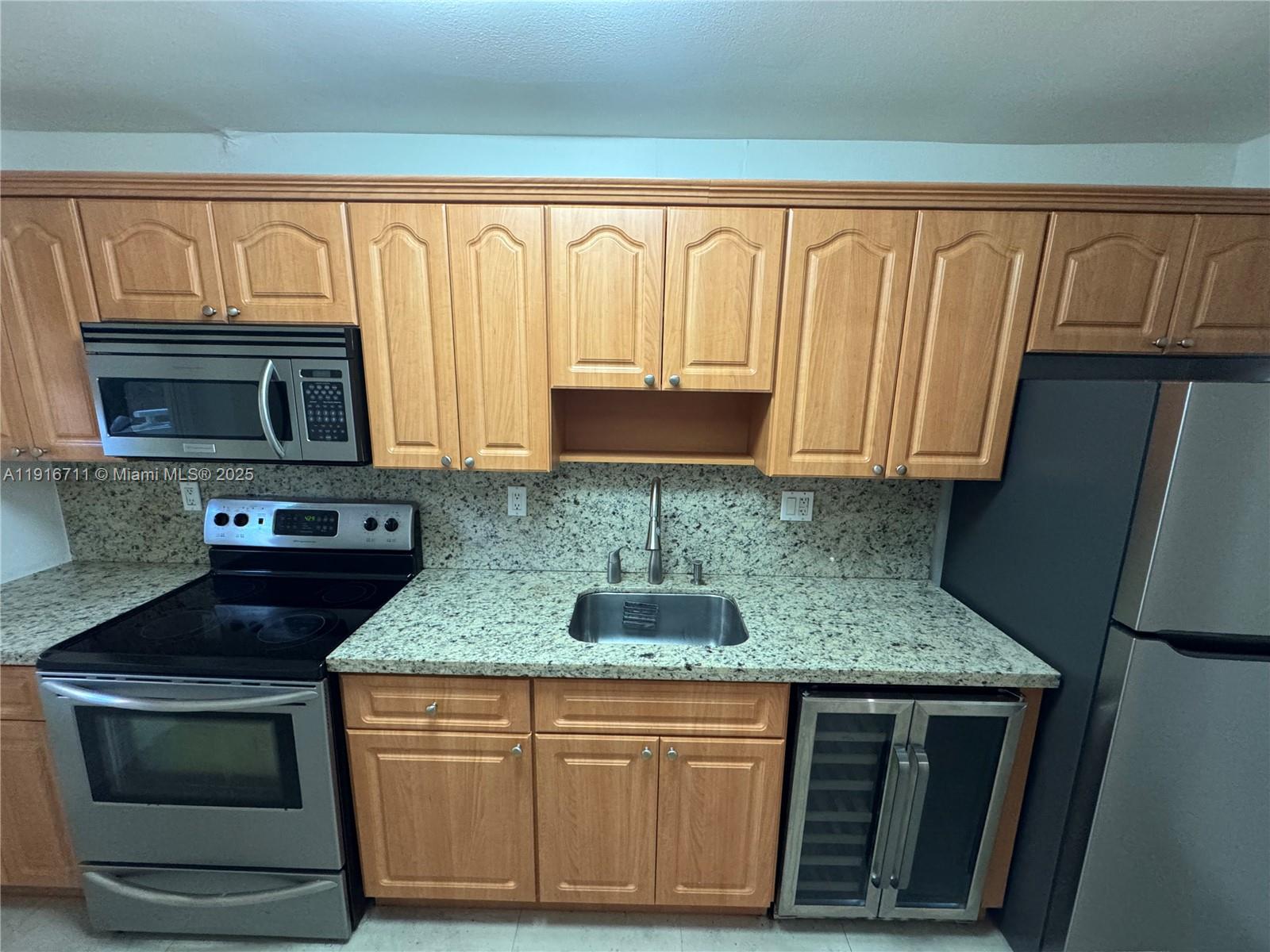5839 Southwest 74th Terrace, Unit 104 South Miami, FL 33143 - Photo 4 of 25 a kitchen with granite countertop a sink stove and microwave