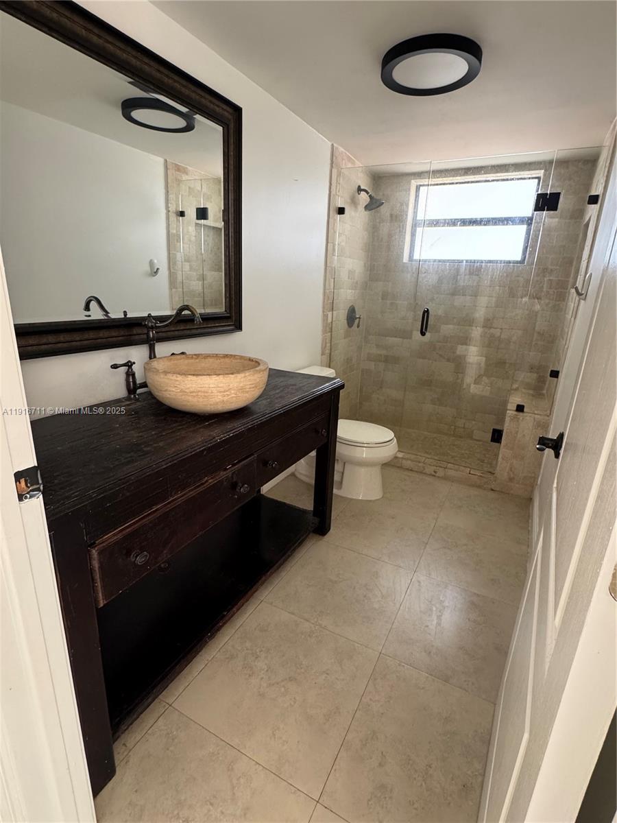 5839 Southwest 74th Terrace, Unit 104 South Miami, FL 33143 - Photo 8 of 25 a bathroom with a sink a toilet a mirror and shower