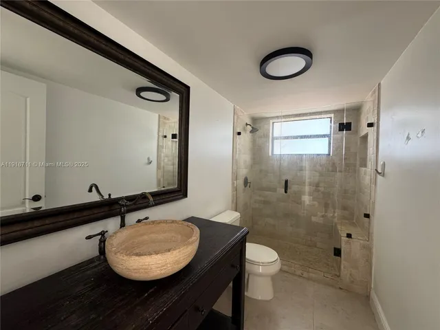 a bathroom with a granite countertop sink toilet a mirror and shower