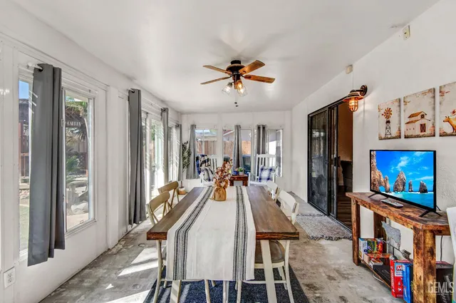 a view of a dining room with furniture a floor to ceiling window and a flat screen tv
