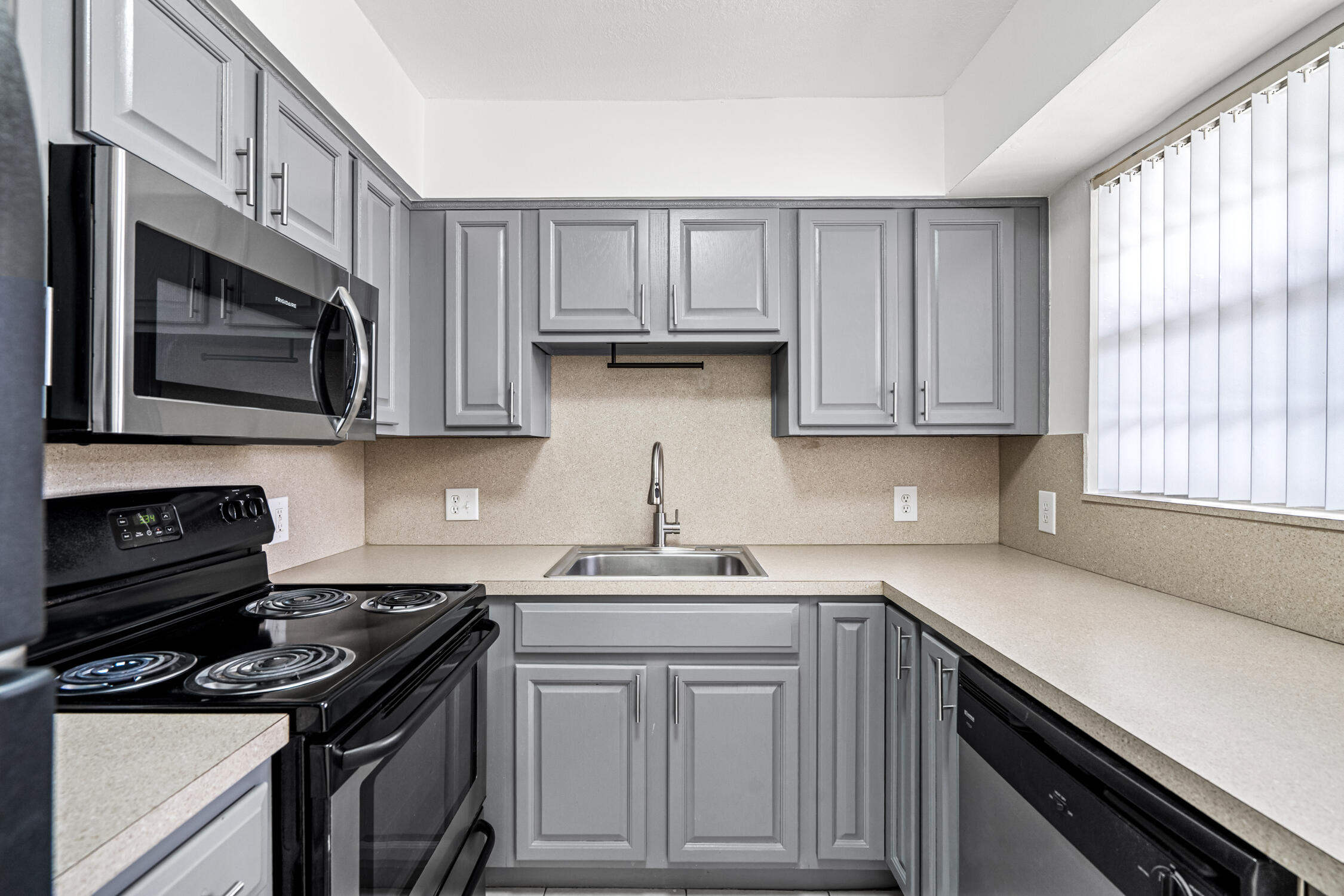 1908 Northwest 4th Avenue, Unit 207 Boca Raton, FL 33432 - Photo 4 of 10 a kitchen with stainless steel appliances granite countertop white cabinets and a stove top oven