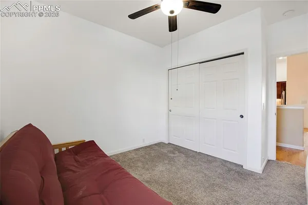 a living room with a bed and a ceiling fan