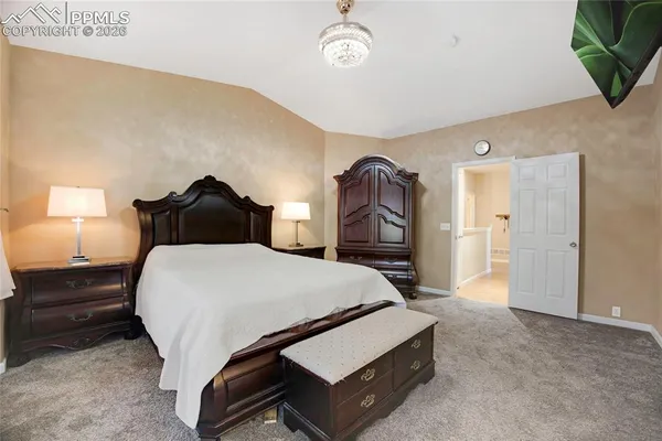 a bedroom with a bed a mirror and a lamp on dresser