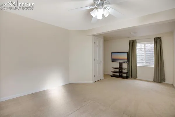 an empty room with windows and chandelier fan
