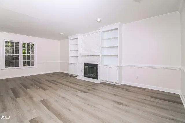 a view of empty room with wooden floor and fireplace