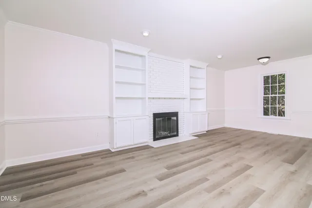 a view of an empty room with a fireplace and a window