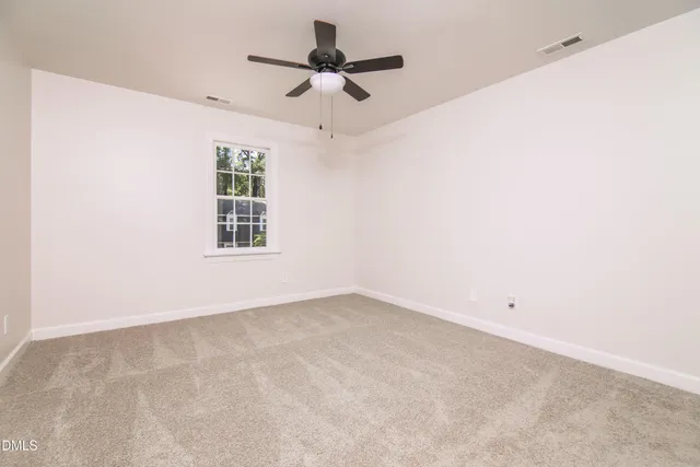 an empty room with a ceiling fan and window