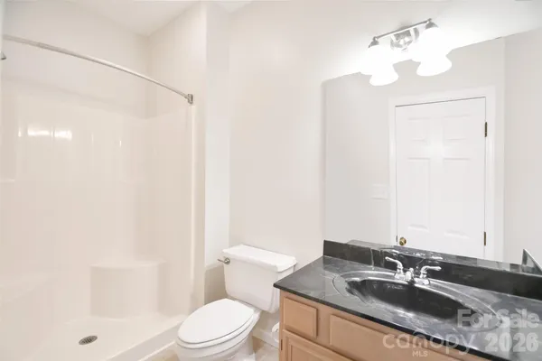 a bathroom with a granite countertop sink a toilet and shower
