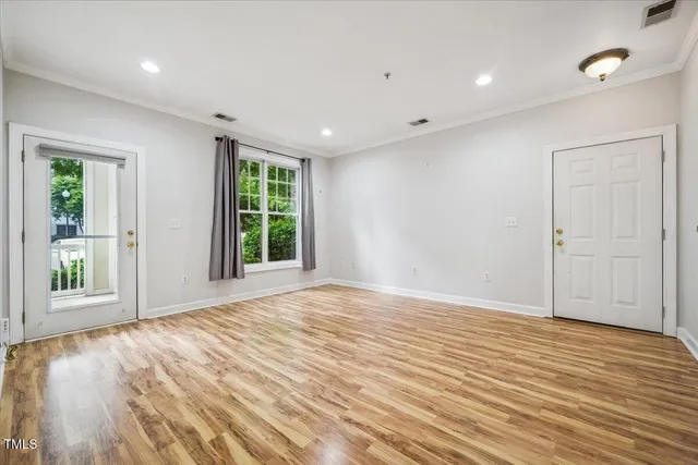a view of an empty room with wooden floor and a window