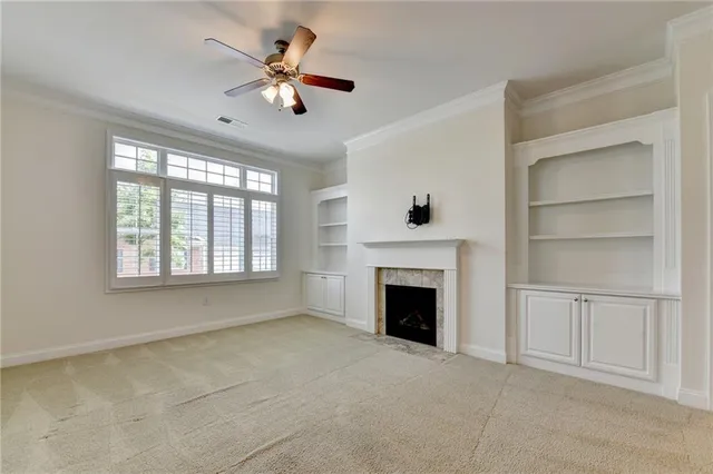 a view of an empty room with chandelier fan and fire place