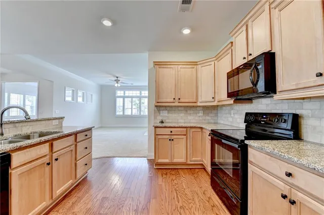 a kitchen with stainless steel appliances granite countertop wooden cabinets granite counter tops and a hard wood floors