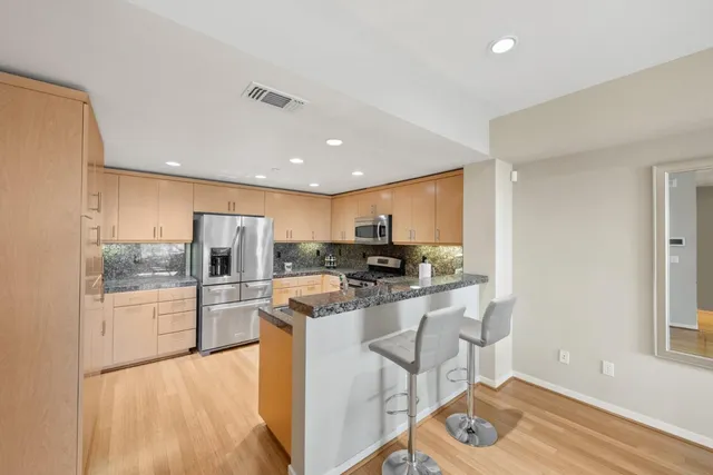 a kitchen with stainless steel appliances granite countertop a refrigerator and a stove top oven