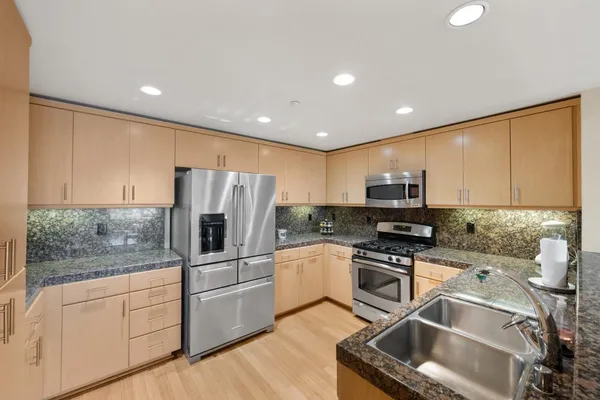 a kitchen with stainless steel appliances granite countertop a refrigerator sink and stove