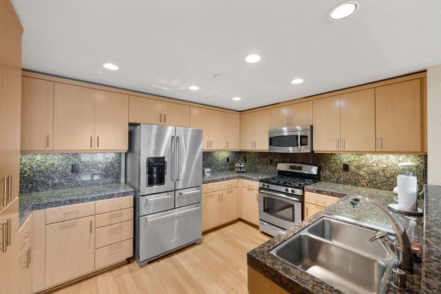 a kitchen with stainless steel appliances granite countertop a refrigerator sink and stove