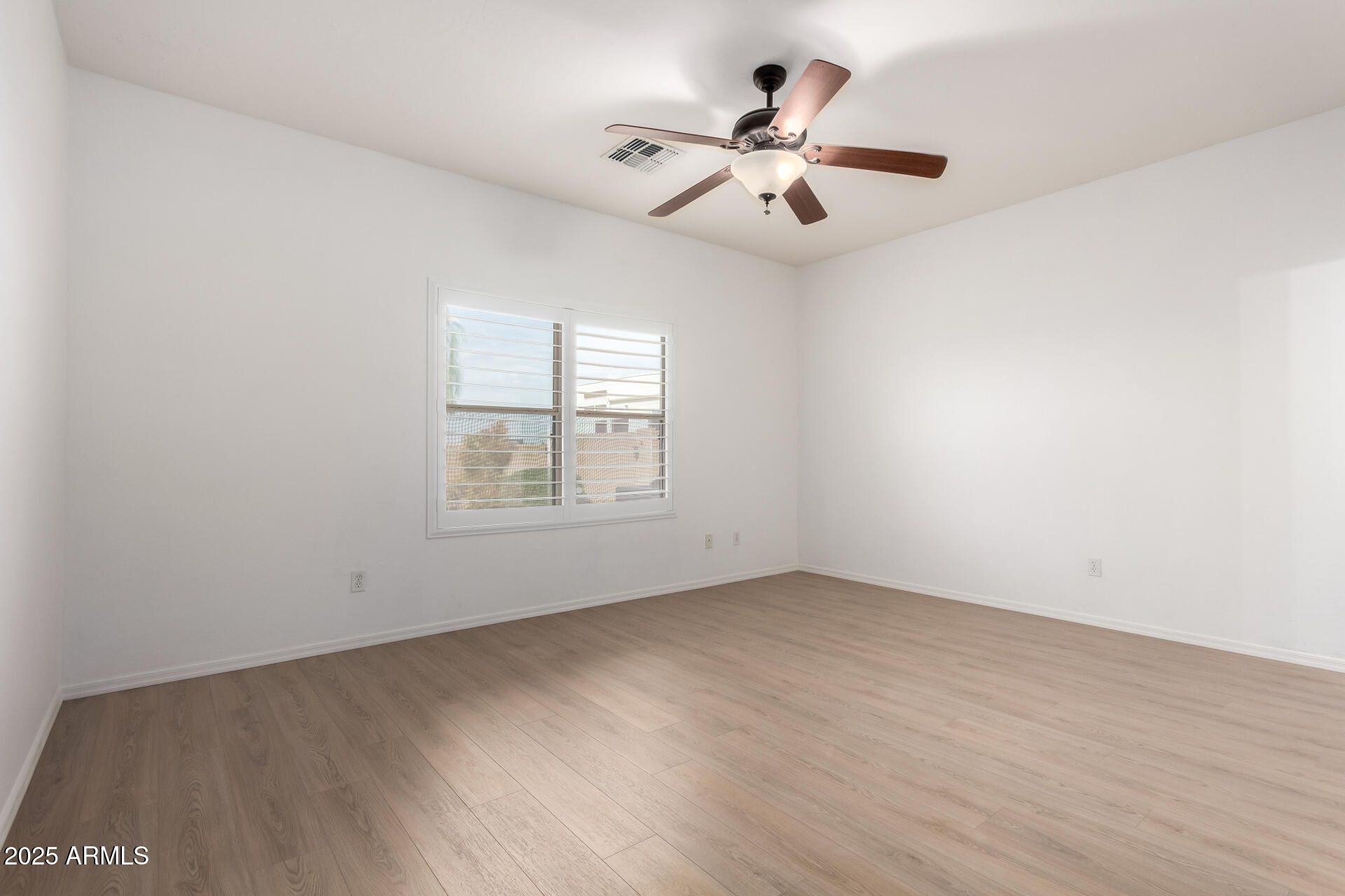 1126 East Pedro Road Phoenix, AZ 85042 - Photo 12 of 34 an empty room with wooden floor chandelier fan and windows